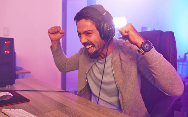 istock Winner, achievement or man gamer on computer with microphone celebrating game win and success fist. Happy, cheering or esport player celebration for online competition, excited on gaming progress 1492874048