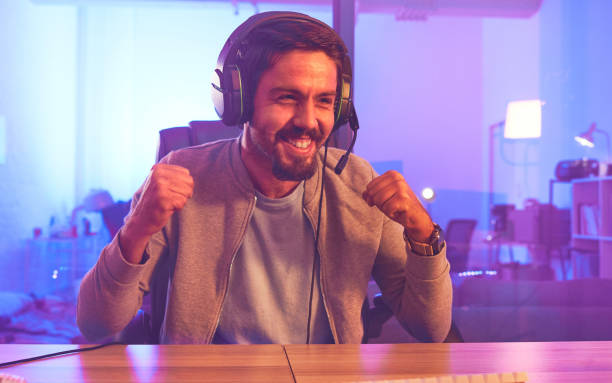 istock Winner, wow or man gamer on computer with microphone celebrating game win and success fist. Happy, cheering or esport player celebration for online competition, excited with progress and achievement 1492874232