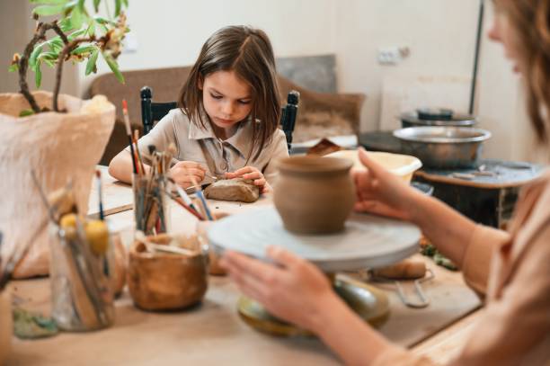 istock Mother with little girl making ceramic pot in the workshop 1492874339