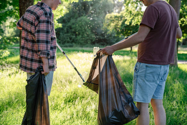 istock Volunteers collect a discarded plastic bottle from grass into a black trash bag. 1492880960