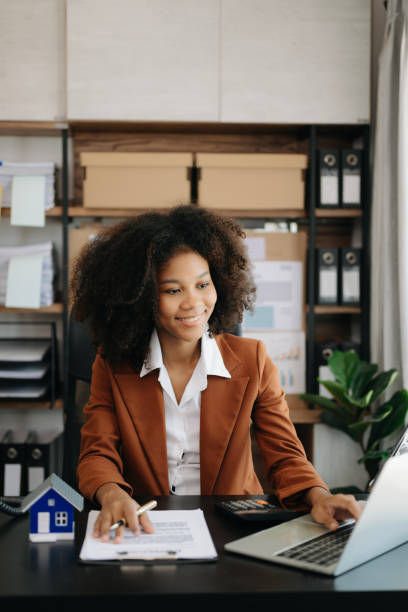 istock Young real estate agent worker working with laptop and tablet at table in office and small house beside it. 1492884580