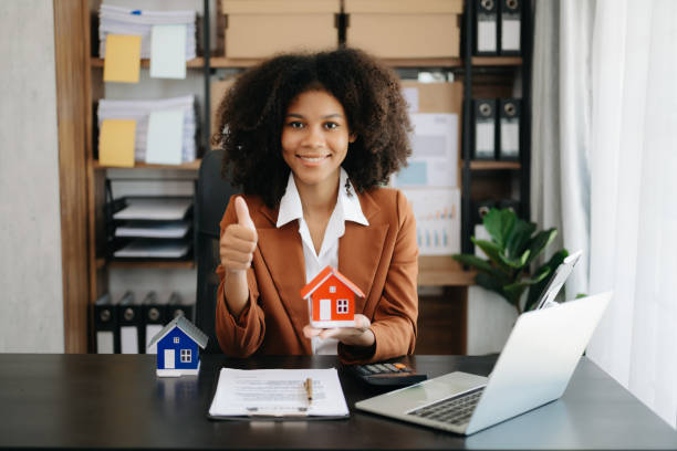 istock Young real estate agent worker working with laptop and tablet at table in office and small house beside it. 1492884638