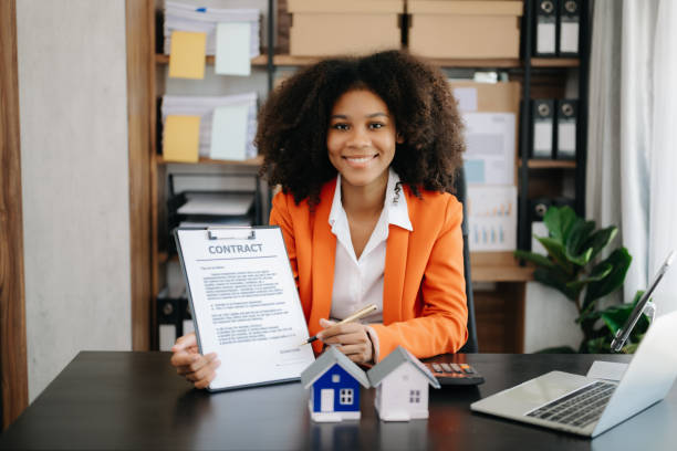 istock Young real estate agent worker working with laptop and tablet at table in office and small house beside it. 1492884656