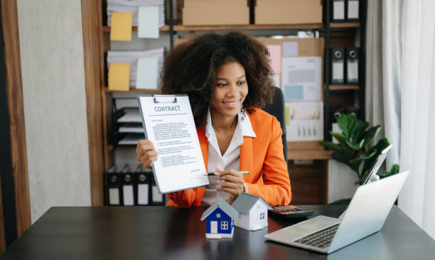 istock Young real estate agent worker working with laptop and tablet at table in office and small house beside it. 1492884724