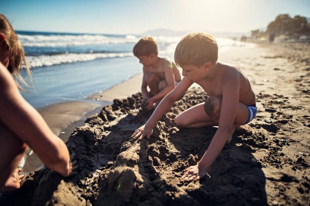 istock Three kids building sand walls on the beach on sunset 1492887215