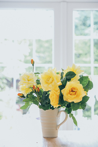 Yellow rose bouquet in vase on dining table