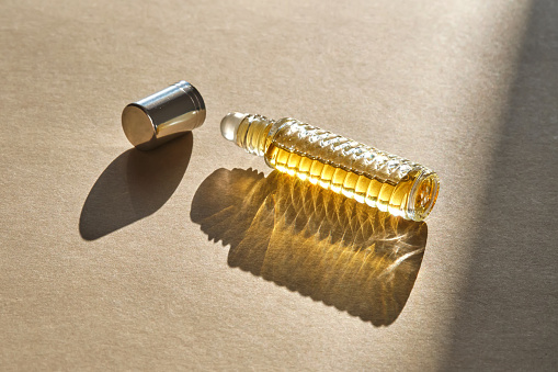 Unrecognizable woman showing perfume to camera in front of white background.