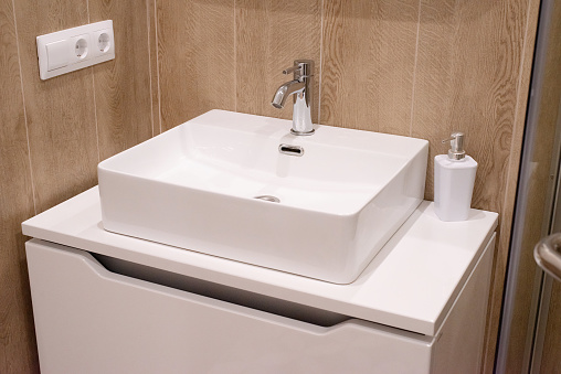 small modern bathroom interior in white and brown colors, bathroom interior, white sink and soap dispenser