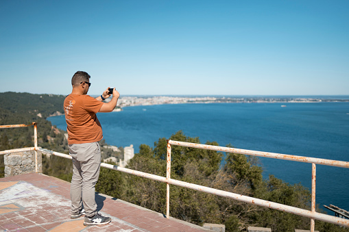 Tourist taking photo of sea view at Serra da Arrábida in Setúbal, Portugal