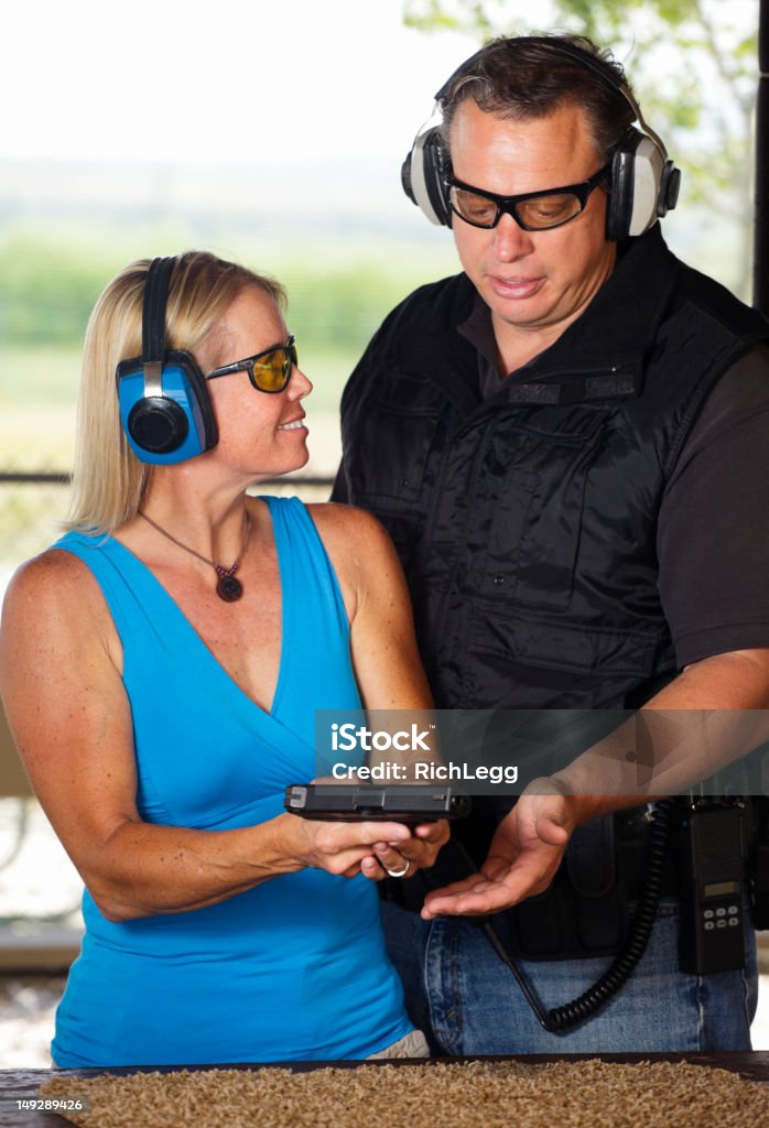 Firearm Instructor and Student A firearm shooting instructor assisting a student at a shooting range. Gun Stock Photo