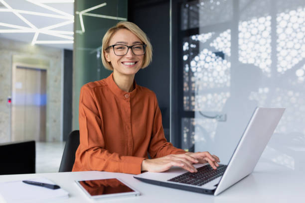 istock Portrait of happy and successful female programmer inside office at workplace, worker smiling and looking at camera with laptop, blonde businesswoman is satisfied with results of achievements at work 1492896553