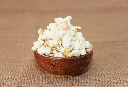 White fried airy popcorn in a plate on a brown background