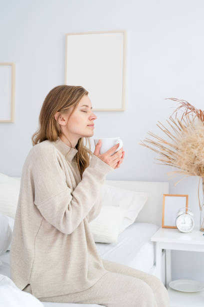 istock Woman sitting at bed at home drinking coffee 1492903096