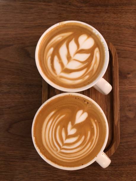 istock Two cappuccino coffee cups with the heart shape closeup top view, rustic wooden background. 1492906103