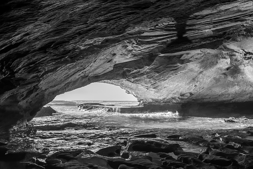 Inside the Waenhuiskrans Cave near Arniston in the Western Cape Province. The Indian Ocean is visible. Monochrome