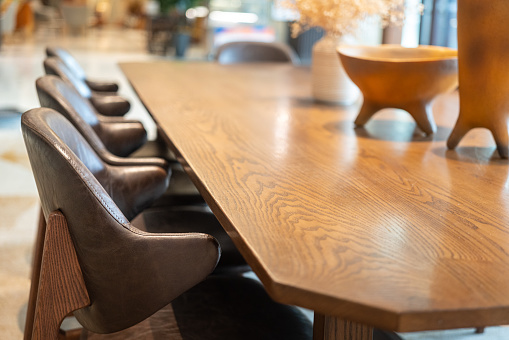 Set of brown leather chairs with classic designed wooden table at the restaurant or hotel lobby. Interior furniture and object photo, selective focus.