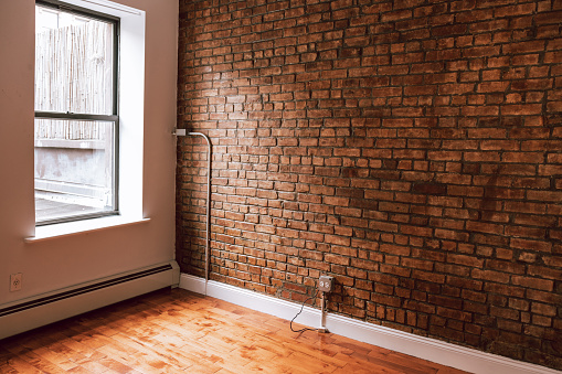 Empty New York studio with a brick wall beside a window. Empty location rental space.