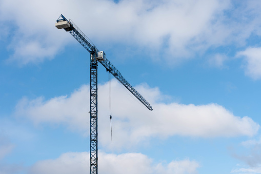 Crane boom against the blue sky. A raised construction crane against the blue sky and white clouds.