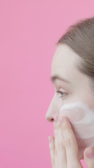 Slow motion Young lady applying face wash foam. Skin care routine