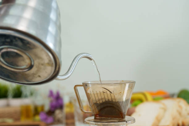 istock Asian hand close up pouring hot water from kettle into coffee cup placed on  jug for drip coffee Let coffee water drip down below. In morning of the day before work Get ready to drink with breakfast. 1492921549