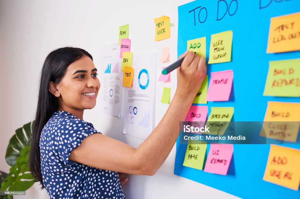 Indian woman writes ticket in backlog of colourful scrum board, KANBAN coding Indian woman writes ticket in backlog of colourful scrum board, KANBAN coding. High quality photo SCRUM - Framework Stock Photo