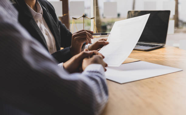 l’avocate explique les termes du document contractuel légal et demande au client de le signer correctement. - avocat photos et images de collection