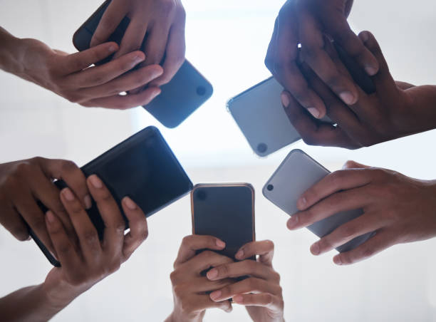 istock Hands, phone and people networking below on social media, mobile app or chatting together. Low angle hand of group with smartphone in circle for online network share, data sync or team communication 1492925877