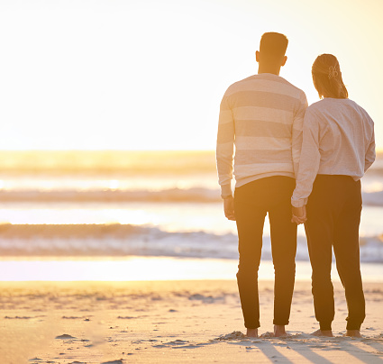 Couple, beach and holding hands at sunset for love and peace with a calm ocean on vacation. Young man and woman together on holiday at sea to relax, travel and connect in nature for freedom mockup
