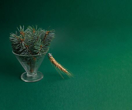 Stylized Christmas tree with a toy in the form of a spikelet on a green background with copy space. Christmas tree on teal background. The concept of hunger, lack of food