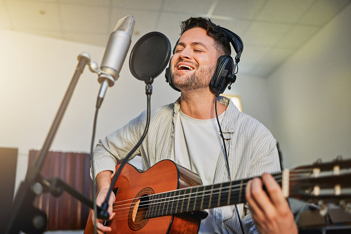 Guitar, microphone and singing in studio for album recording, theatre label or radio musician industry. Man, singer and guitarist headphones for instrument production, theater sound or karaoke media