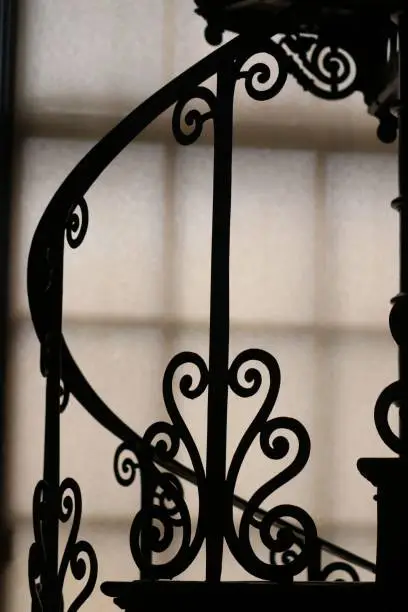 A vintage-style metal railing silhouetted against a bright window