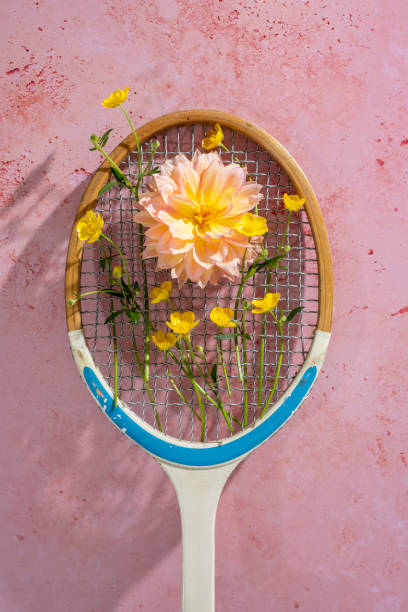 istock Vintage Tennis Racket on a textured pink background, with flowers threaded through the strings. 1492936985