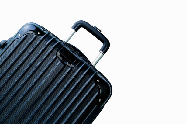 Unrecognizable person pulling trolley luggage at airport. Note to inspector: luggage in background has been blurred