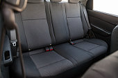 Close-up on rear seats with velours fabric upholstery in the interior of an old Korean car in gray after dry cleaning. Auto service industry.