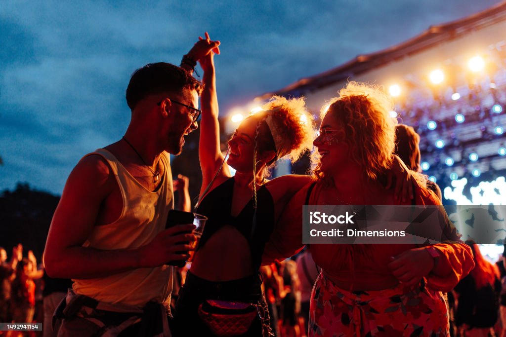 Friends having fun drinking beer and dancing at concert Group of happy friends having fun while dancing and drinking beer on a music concert. Music Festival Stock Photo