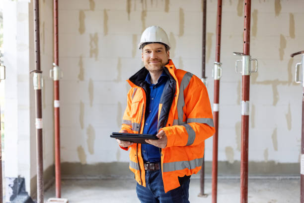 строитель стоит на стройке - manual worker portrait helmet technology стоковые фото и изображения