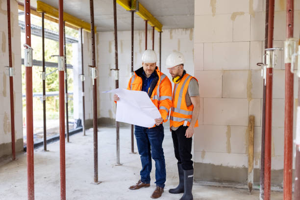 istock Two engineers standing in an unfinished structure at construction site reviewing a blueprint 1492941424