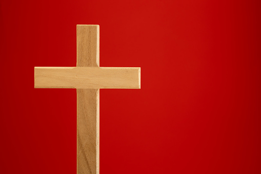 Small wood Christian cross on a red background with copy space