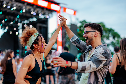 A joyful young Caucasian couple is dancing at a music festival day party.