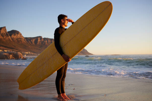 istock Surfer, man and beach with looking, waves and hand by eyes for safety from sun, thinking or planning morning. Ocean athlete, surfboard or water for fitness, sports and tropical adventure for exercise 1492945349
