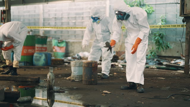 Scientists picking biohazardous samples in the infected factory area. Group of scientists in protective workwear exploration and picking samples for analysis.