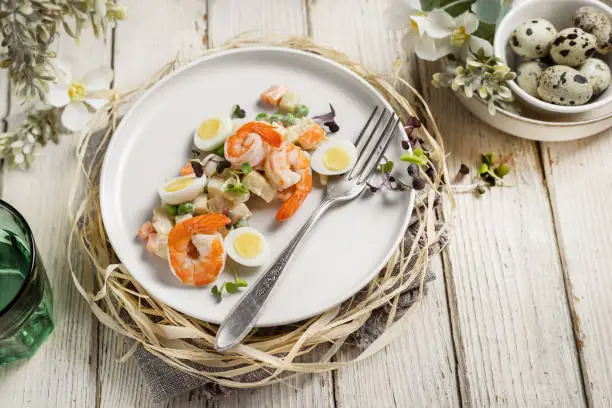 Shrimps salad with boiled eggs and vegetables on rustic wooden board, cold appetizer served on the table