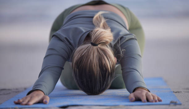 Woman, yoga and stretching on beach for spiritual wellness, zen or workout in nature. Female yogi in warm up stretch, shishosana pose or pilates for healthy exercise or fitness by the ocean coast Woman, yoga and stretching on beach for spiritual wellness, zen or workout in nature. Female yogi in warm up stretch, shishosana pose or pilates for healthy exercise or fitness by the ocean coast childs pose stock pictures, royalty-free photos & images