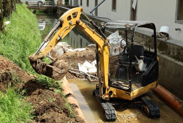 istock Compact excavator at work in a canal bed to maintenance the embankments. 1492952872