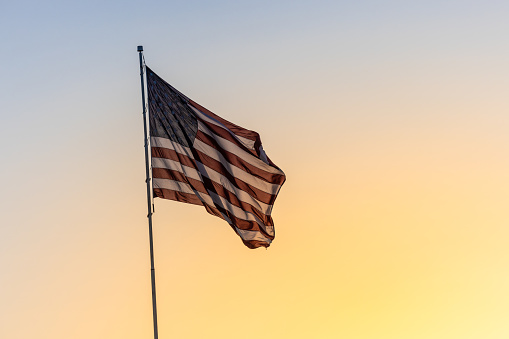 American USA flag against a sunrise or sunset background