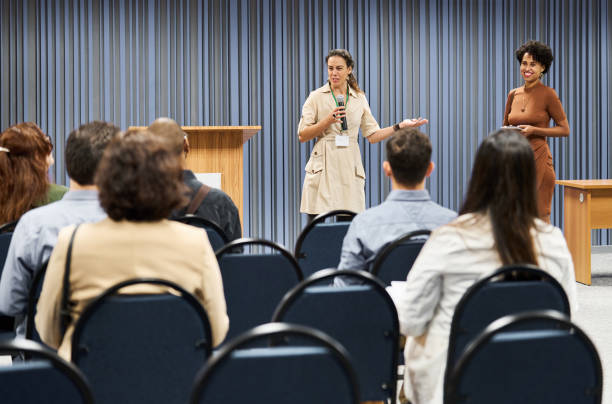 istock Businesswoman with a microphone introducing a speaker during a seminar in a conference center 1492954752