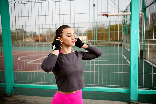 Shot of young woman putting her earphones in before a running session