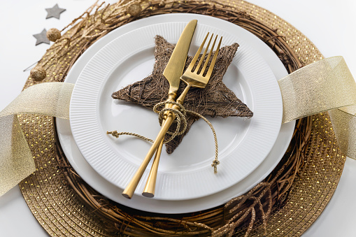 Gold festive place setting table arrangement with wooden star; holiday dining table 
decoration; Christmas dinner preparation
