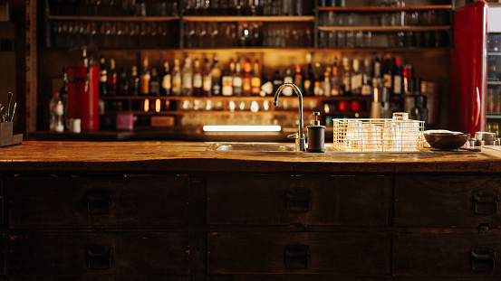 Photography of vintage bar and blurred shelves with liquor bottles in the background.