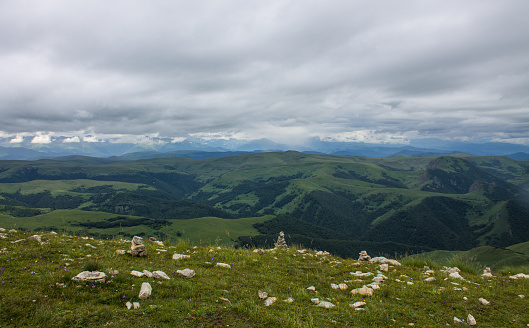Fantastic dramatic landscape - panoramic view of the hilly valley blurred in the morning fog from the Bermamyt plateau in Karachay Cherkessia on a cloudy summer day
